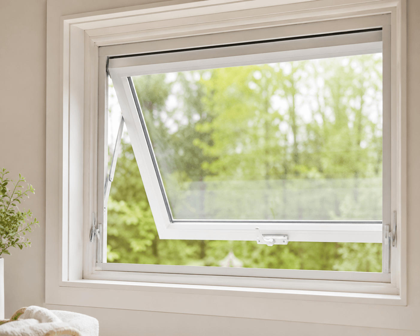 Awning window open with white frame showing garden view with green trees and foliage outside.