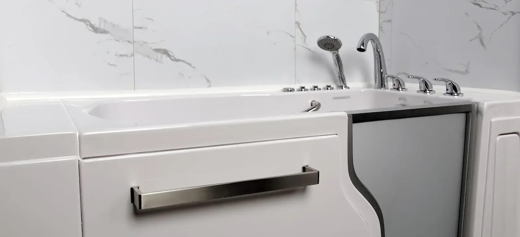 Walk-in bathtub with a stainless steel door handle against a marble-tiled wall. Features include chrome fixtures and a handheld showerhead.