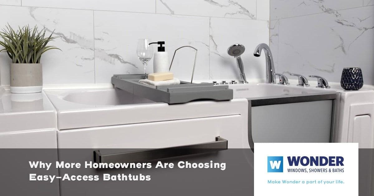 A modern bathroom features an easy-access bathtub with a gray tray holding soap and a wine glass. A plant adds greenery, set against marble tiles. A logo and text highlight the benefits of these bathtubs.