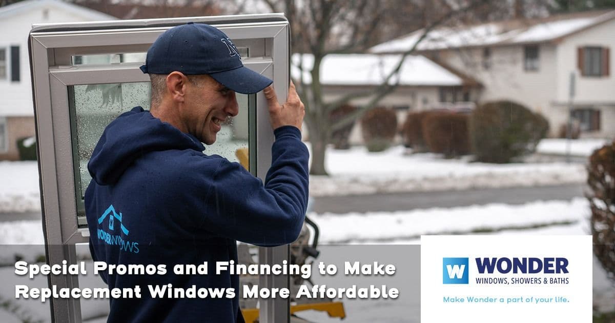 A worker in a blue hoodie carries a window in a snowy suburban neighborhood. Text overlay promotes window replacement deals. Branding shown: "WONDER".