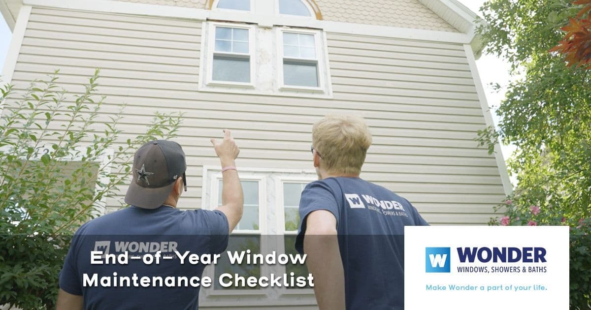 Two people in blue shirts stand outside, pointing at the upper windows of a beige house. Text reads "End-of-Year Window Maintenance Checklist" with a company logo.