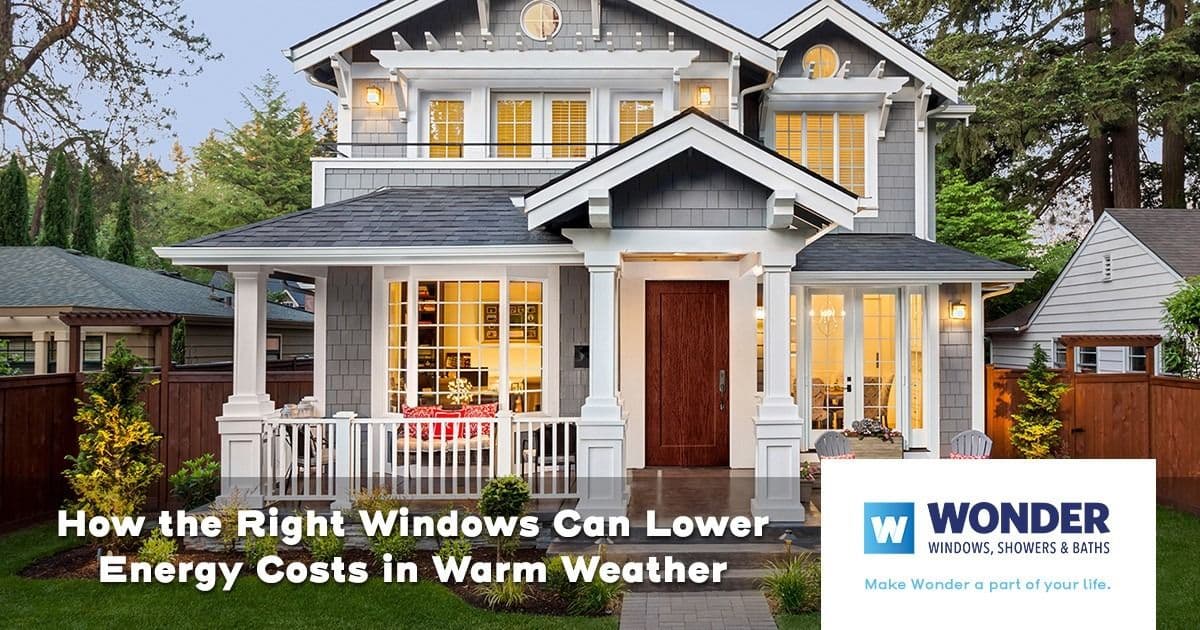 Charming two-story house with large energy-efficient windows. Surrounded by trees, warm light glows inside. Text reads: "How the Right Windows Can Lower Energy Costs in Warm Weather." Logo for Wonder Windows in corner.