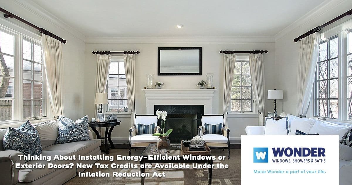 Bright living room with large windows, white curtains, a gray sofa, and a fireplace. Text highlights energy-efficient window tax credits. Wonder logo.