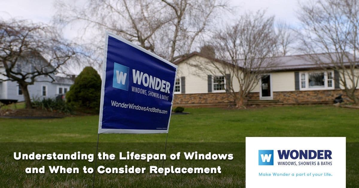 A lawn with a "Wonder Windows, Showers & Baths" sign in front of a house. Text reads, "Understanding the Lifespan of Windows and When to Consider Replacement."