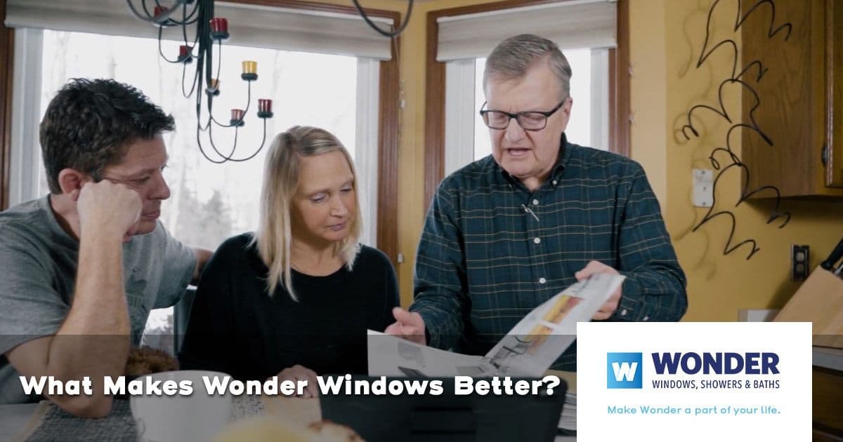 A consultant shows a couple a brochure at a kitchen table, discussing products. Text reads "What Makes Wonder Windows Better?" with Wonder branding.