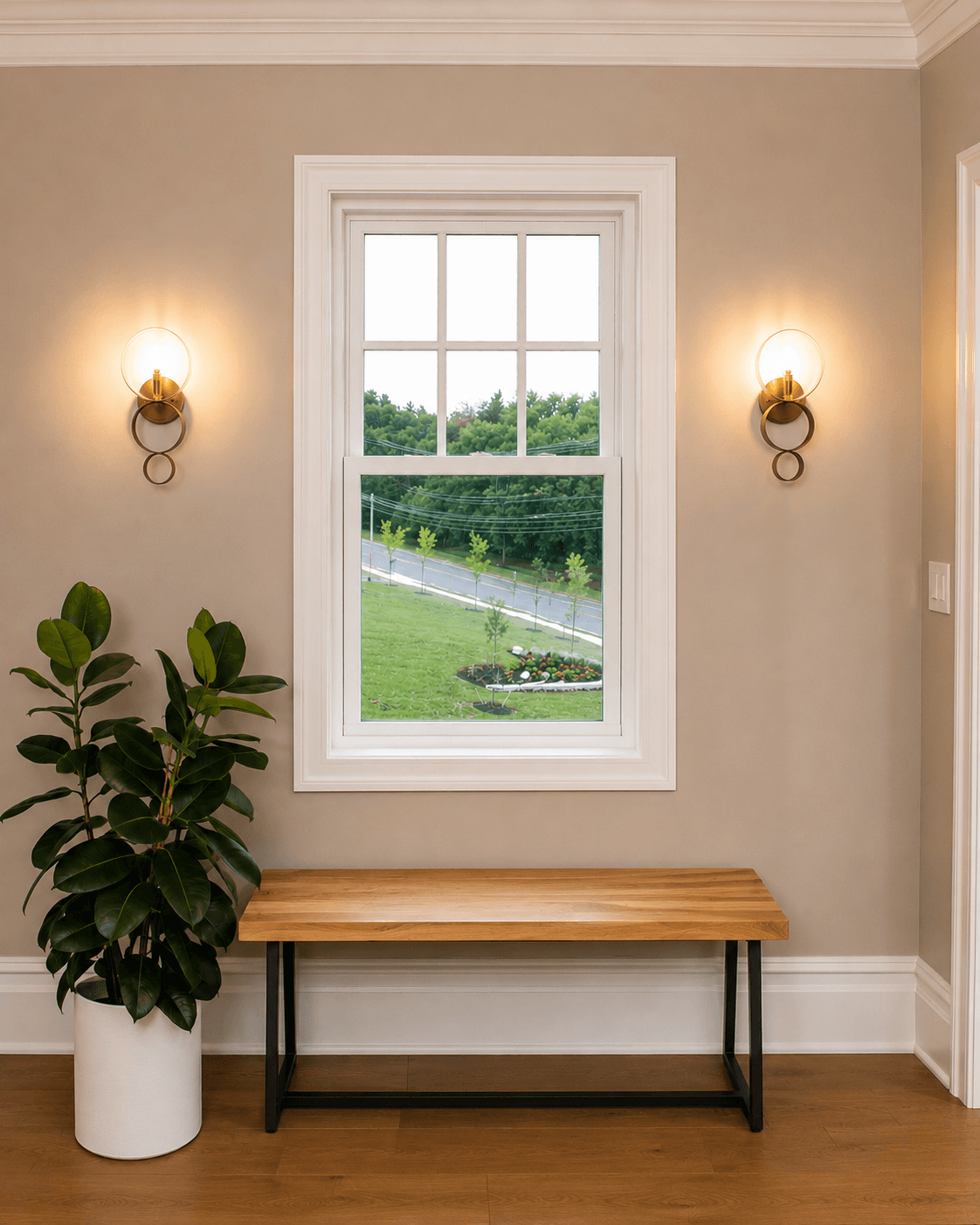 Entryway with wooden bench, potted plant, and double-hung window overlooking landscaped yard with garden bed and fencing.